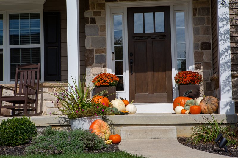 The Signature Porch close on the front door, pumpkins in orange, white and green banked either side with a mum on each side