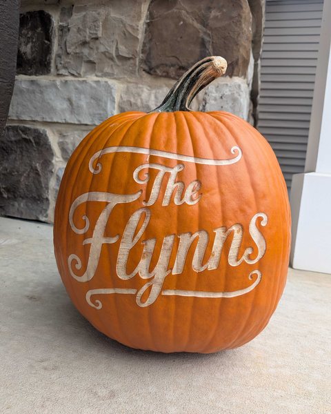 The Flynns, engraved in flowing script on an orange pumpkin