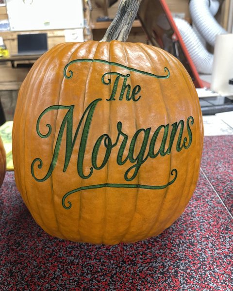 The same engraved pumpkin, its design showing green just after the laser
